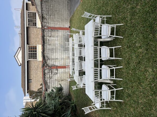 Mesas y sillas blancas en jardín para boda